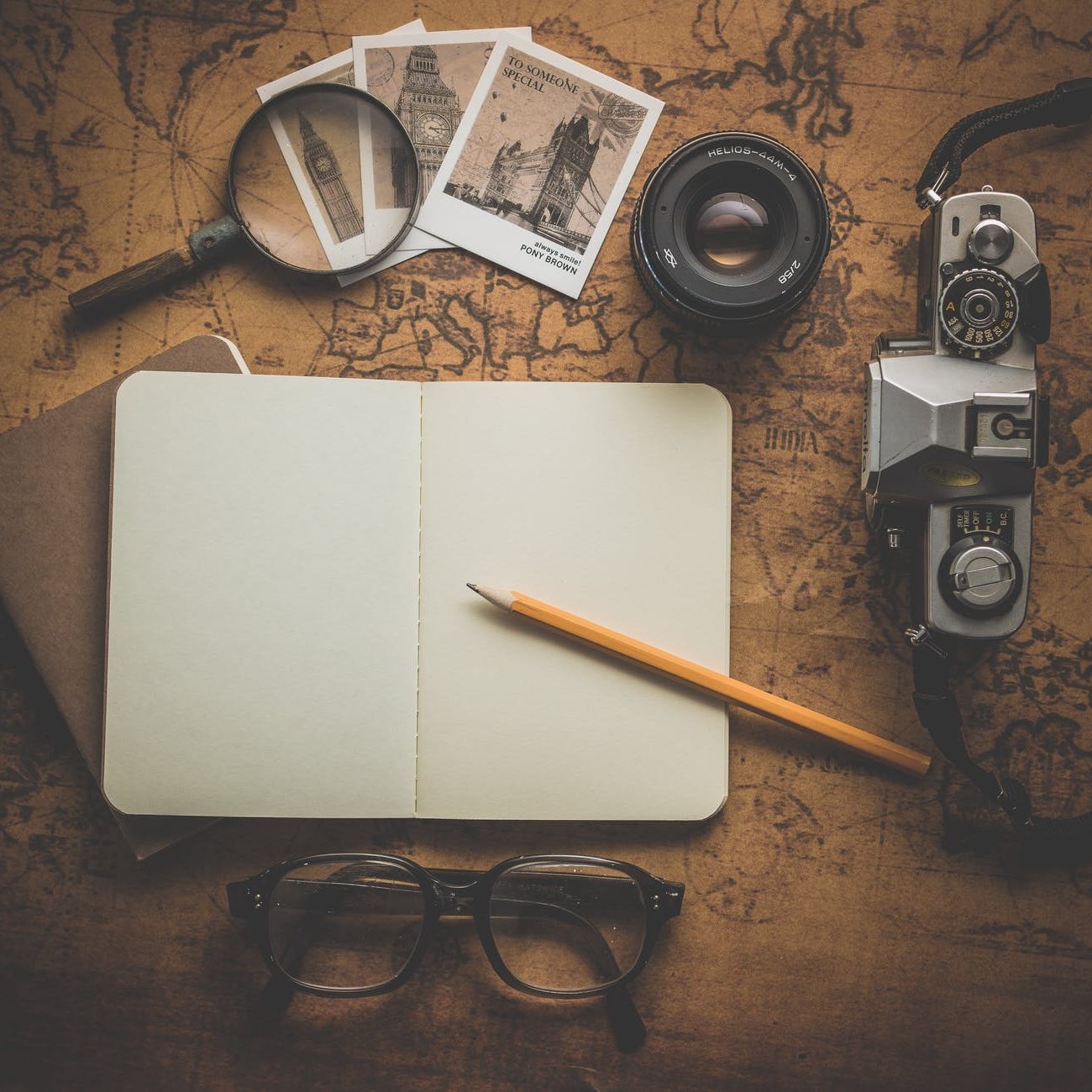 Photograph of a writers notebook, old photos, glasses and a pen.